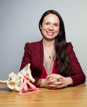 colour photo of bernadett kasza with model of pelvis on a table in front of her