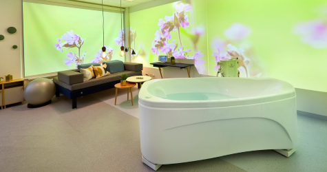View of beautiful birth suite with birthing pool, soft furnishings, flowers on the walls and a birthing ball